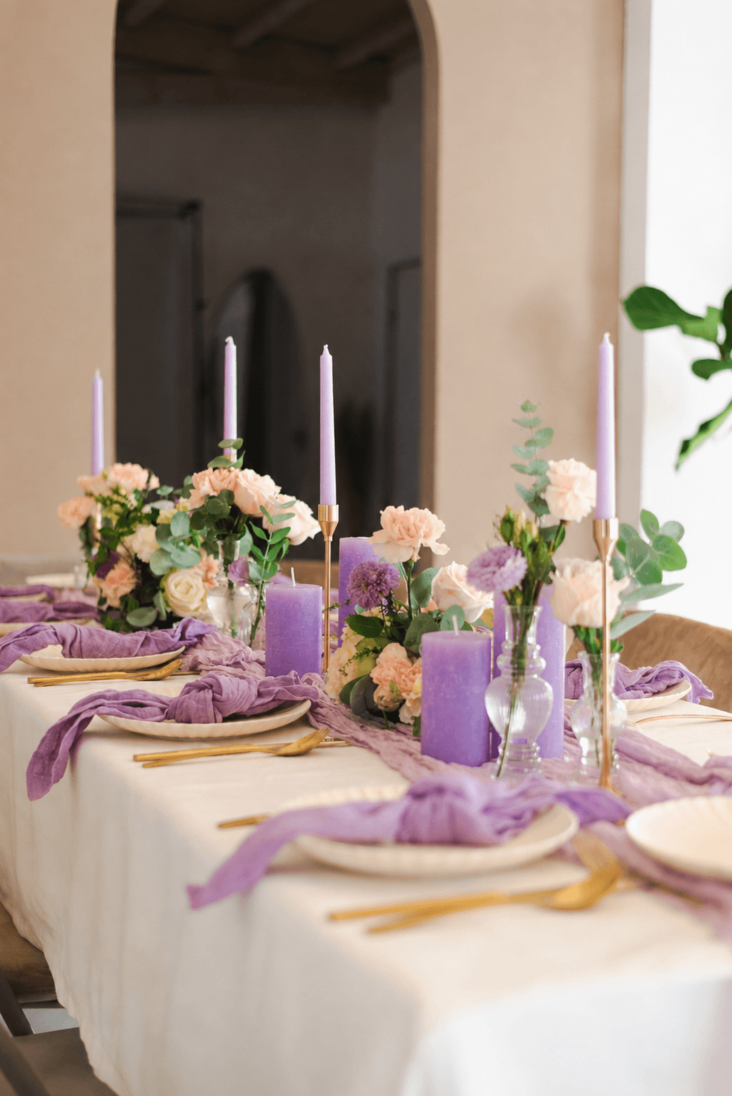 Paarse en perzikkleurige tafelstyling met kaarsen en bloemen